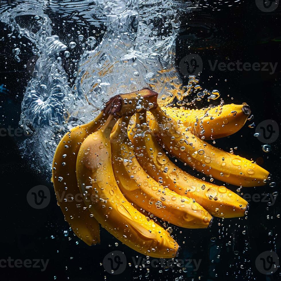 Bananen fallen im Wasser mit Spritzen auf schwarz Hintergrund. foto