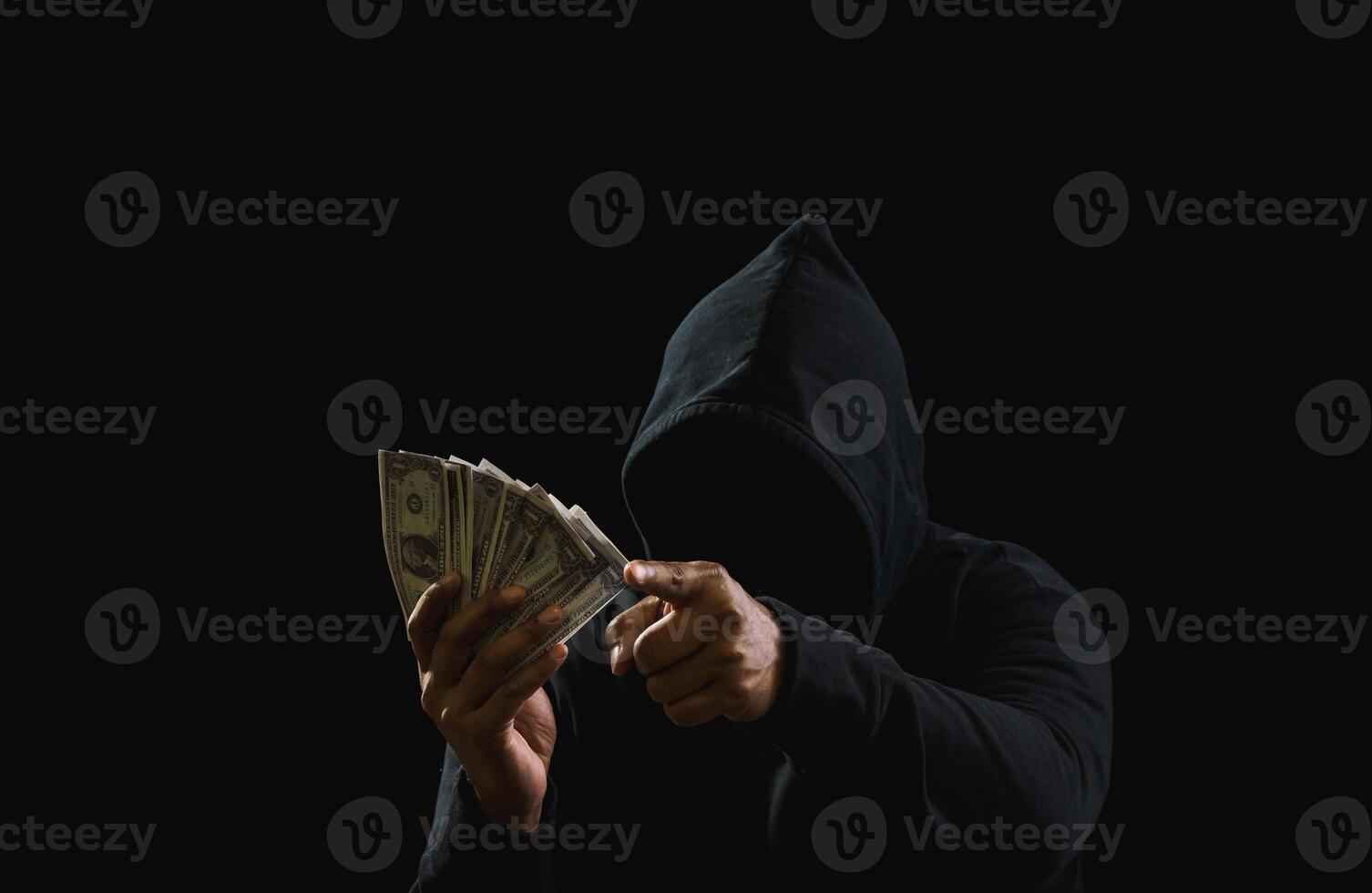 Porträt Mörder Hacker Mafia Gangster Spion Mann eine Person im schwarz Kapuzenpullover Stehen aussehen Hand halten Geld Dollar erhalten von Raub Drohung Verbrechen Attacke Opfer Menschen Nacht dunkel Hintergrund Kopieren Raum foto
