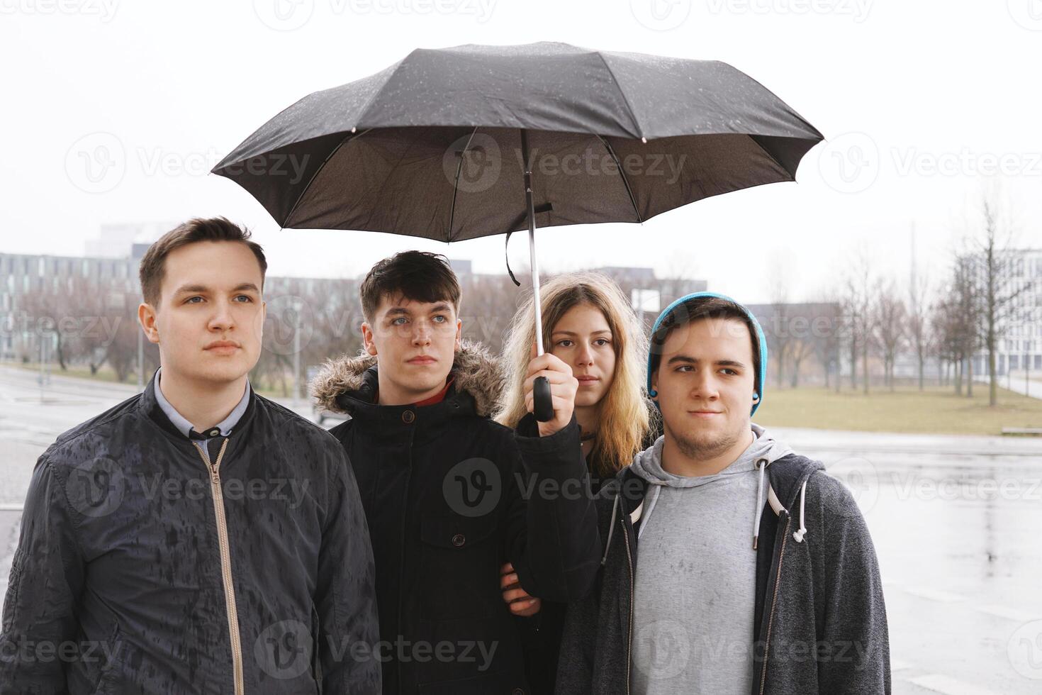 Gruppe von jung städtisch Teenager freunde unter einer Regenschirm foto