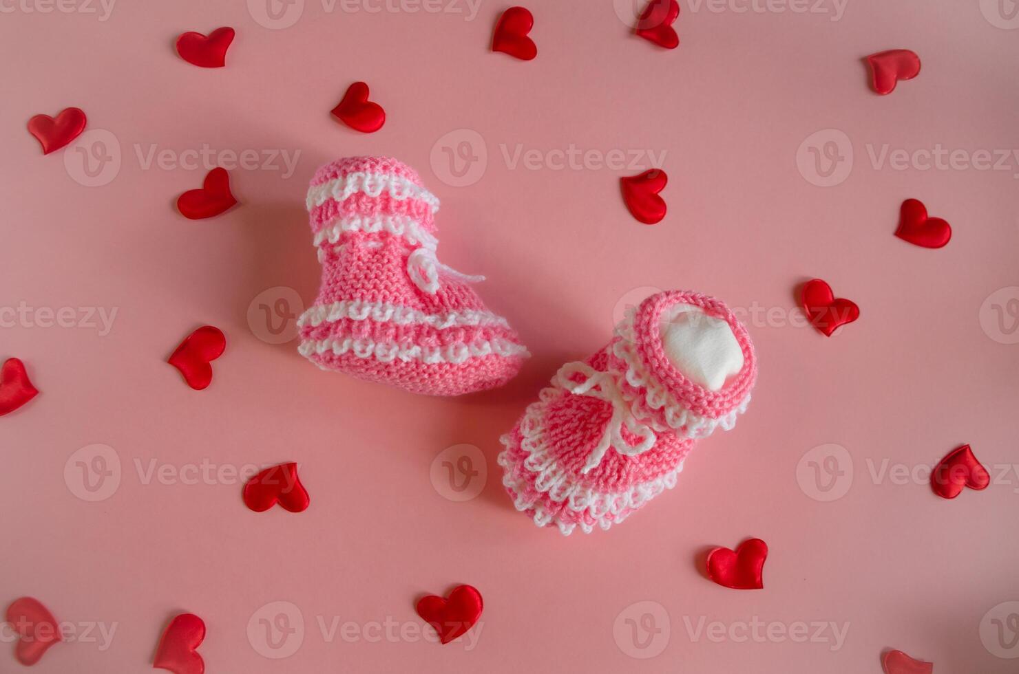 gestrickt Rosa Booties Baby Socken auf Rosa Hintergrund mit Herzen foto