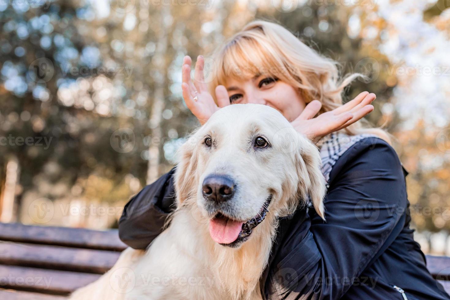 glückliche kaukasische Frau, die mit ihrem Labrador-Retriever-Hund im Park spielt foto
