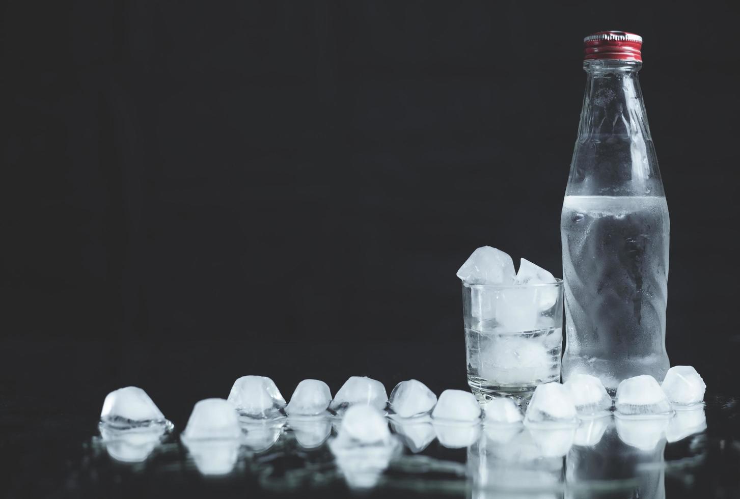 Flasche mit Gläsern Wodka auf schwarzem Hintergrund. foto