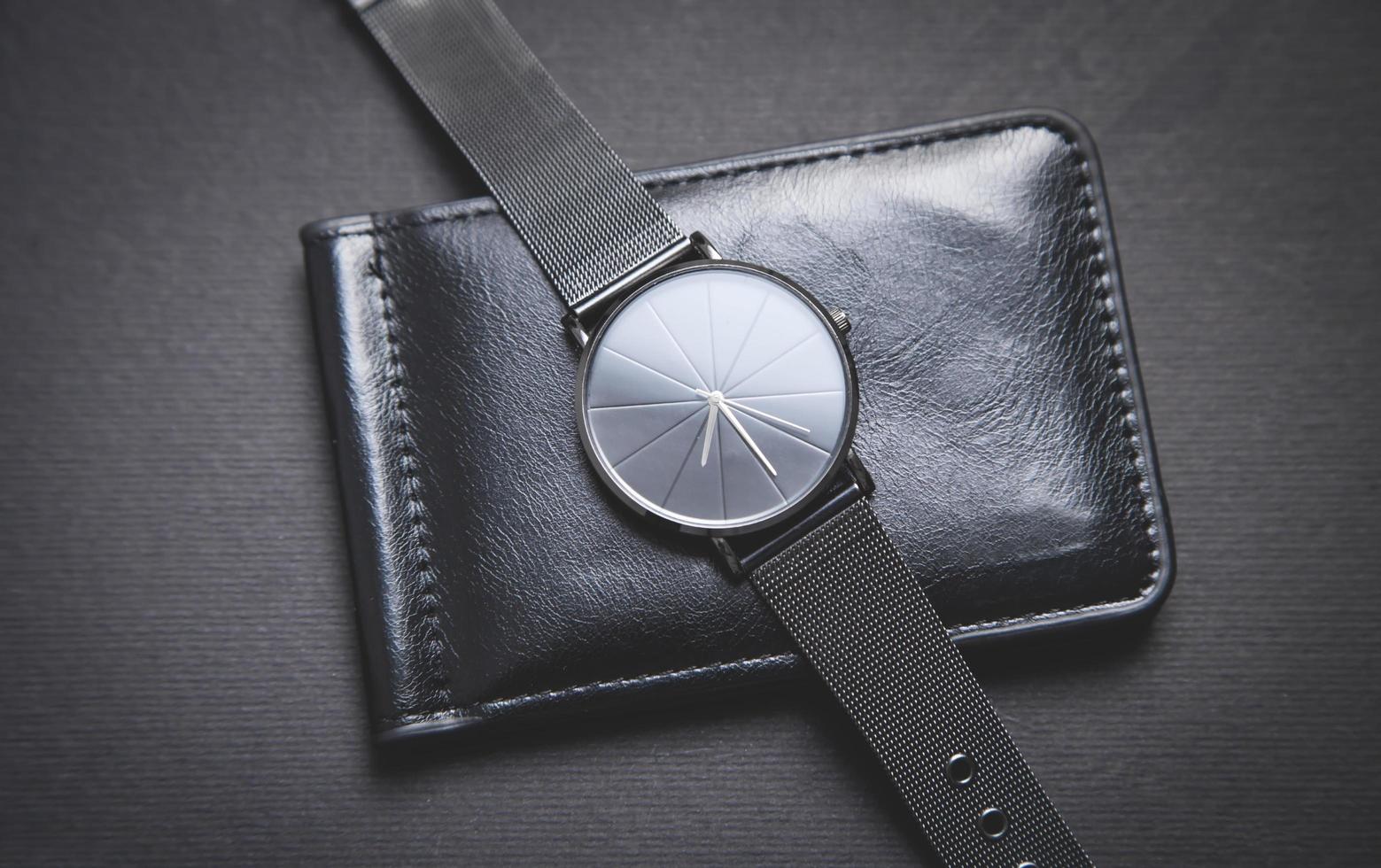 schwarze Armbanduhr und Geldbörse auf schwarzem Hintergrund. foto