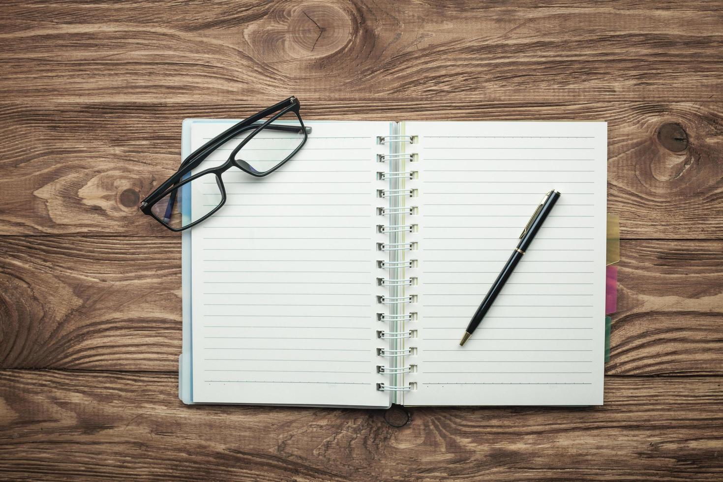 Notizblock-Brille und Stift auf einem hölzernen Hintergrund. foto