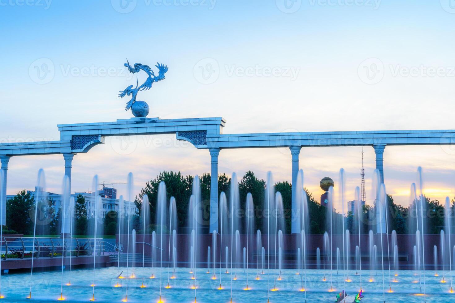 Denkmal und Reihen von Brunnen beleuchtet durch Sonnenlicht beim Sonnenuntergang oder Sonnenaufgang im das Unabhängigkeit Platz beim Sommer, Taschkent. foto