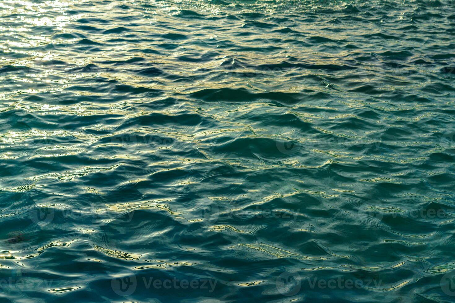 das Textur von das Wellen im Türkis Farbe, beleuchtet durch das Sonne beim Sonnenuntergang oder Dämmerung. Natur Hintergrund. foto