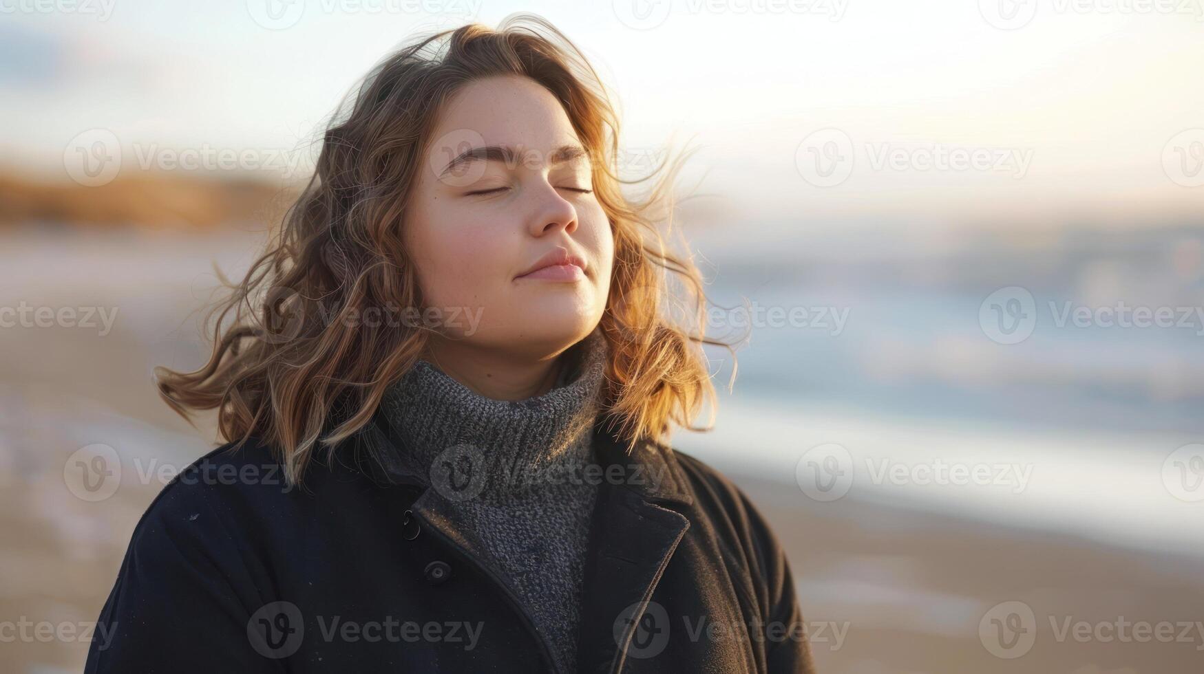 ein Frau im beiläufig Kleidung Stehen auf ein sandig Strand, Augen geschlossen unter das Sonnenlicht foto