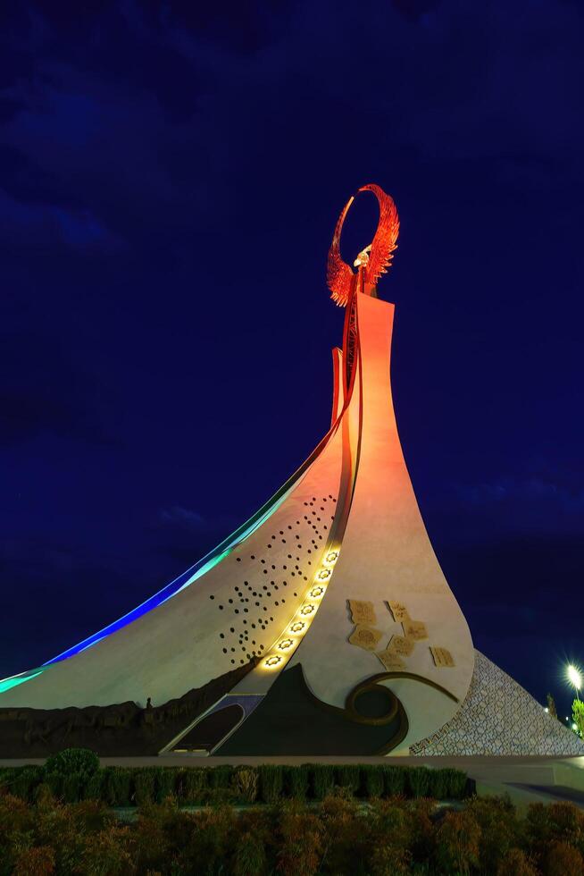 Usbekistan, Taschkent - - Oktober 4, 2023 beleuchtet Monument von Unabhängigkeit im das bilden von ein Stele mit ein Humo Vogel im das Neu Usbekistan Park beim Nachtzeit im Herbst. foto