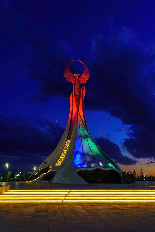 Usbekistan, Taschkent - - Oktober 4, 2023 beleuchtet Monument von Unabhängigkeit im das bilden von ein Stele mit ein Humo Vogel im das Neu Usbekistan Park beim Nachtzeit im Herbst. foto