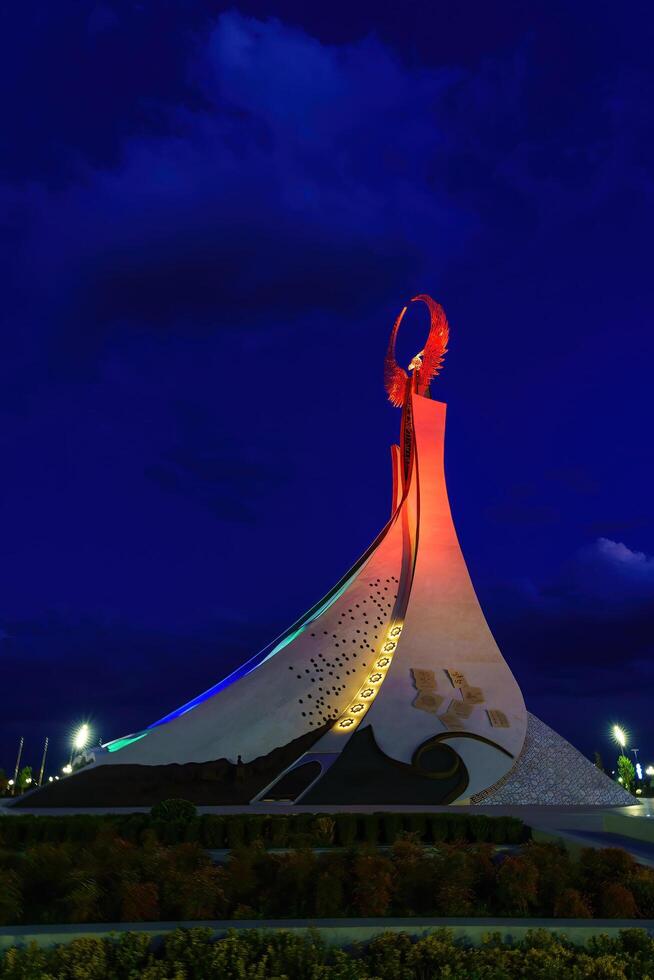 Usbekistan, Taschkent - - Oktober 4, 2023 beleuchtet Monument von Unabhängigkeit im das bilden von ein Stele mit ein Humo Vogel im das Neu Usbekistan Park beim Nachtzeit im Herbst. foto