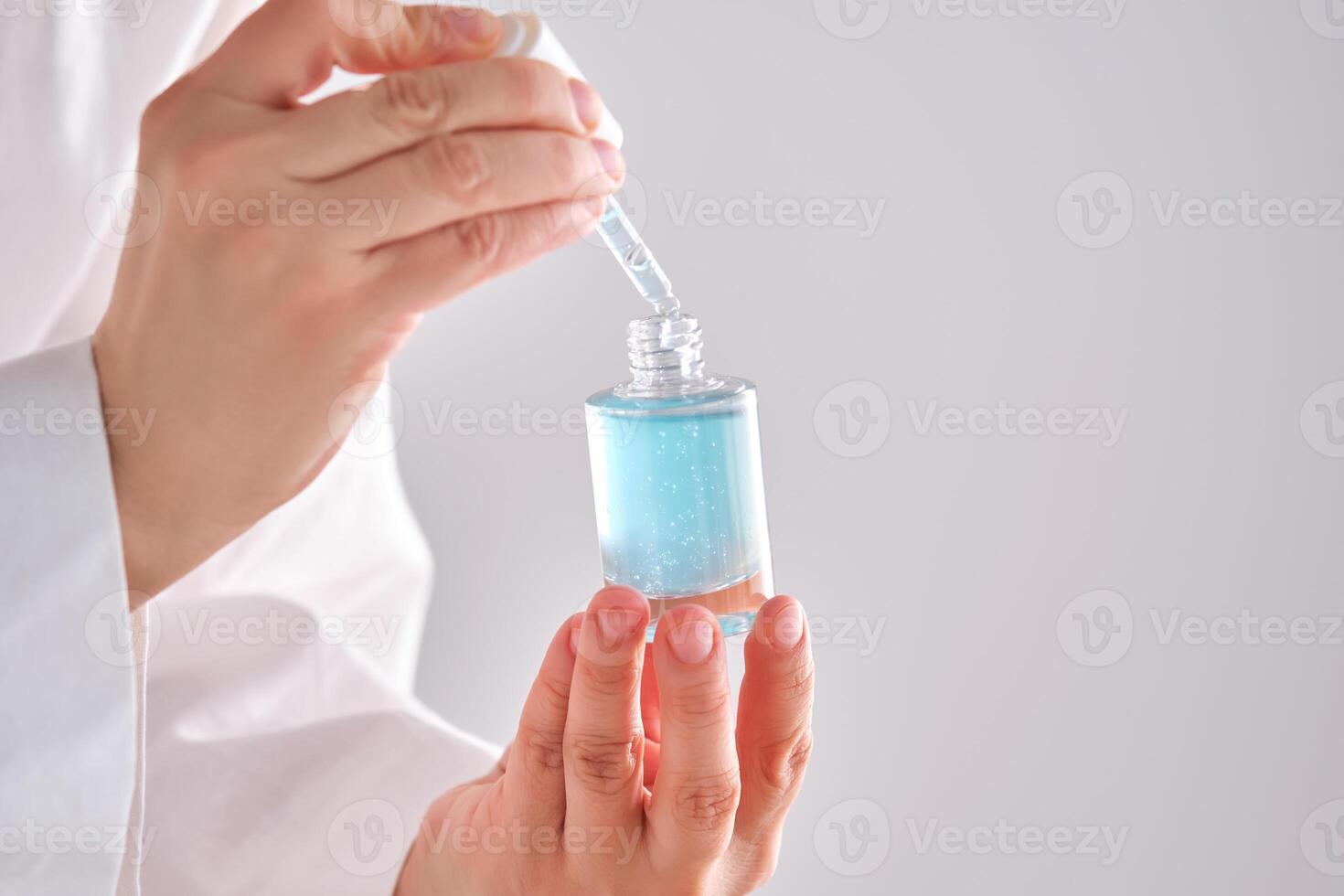 Blau Serum mit Pipette im ein Frauen Hände im ein Kleid. foto