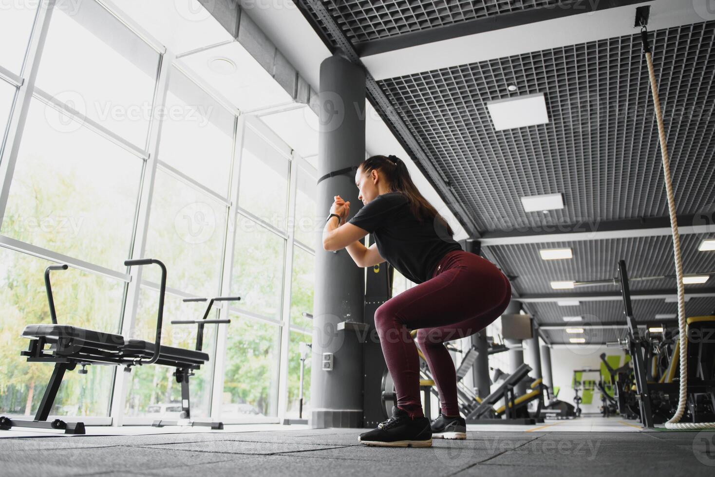 Seite Aussicht Porträt von ein jung Frau tun Kniebeugen beim Fitness Fitnessstudio. foto