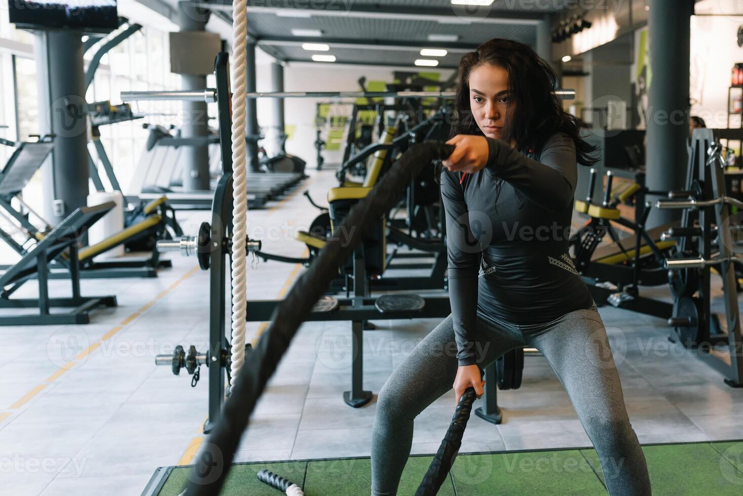 ziemlich spanisch jung Frau tun etwas Crossfit Übungen mit ein Seil beim ein Fitnessstudio. foto