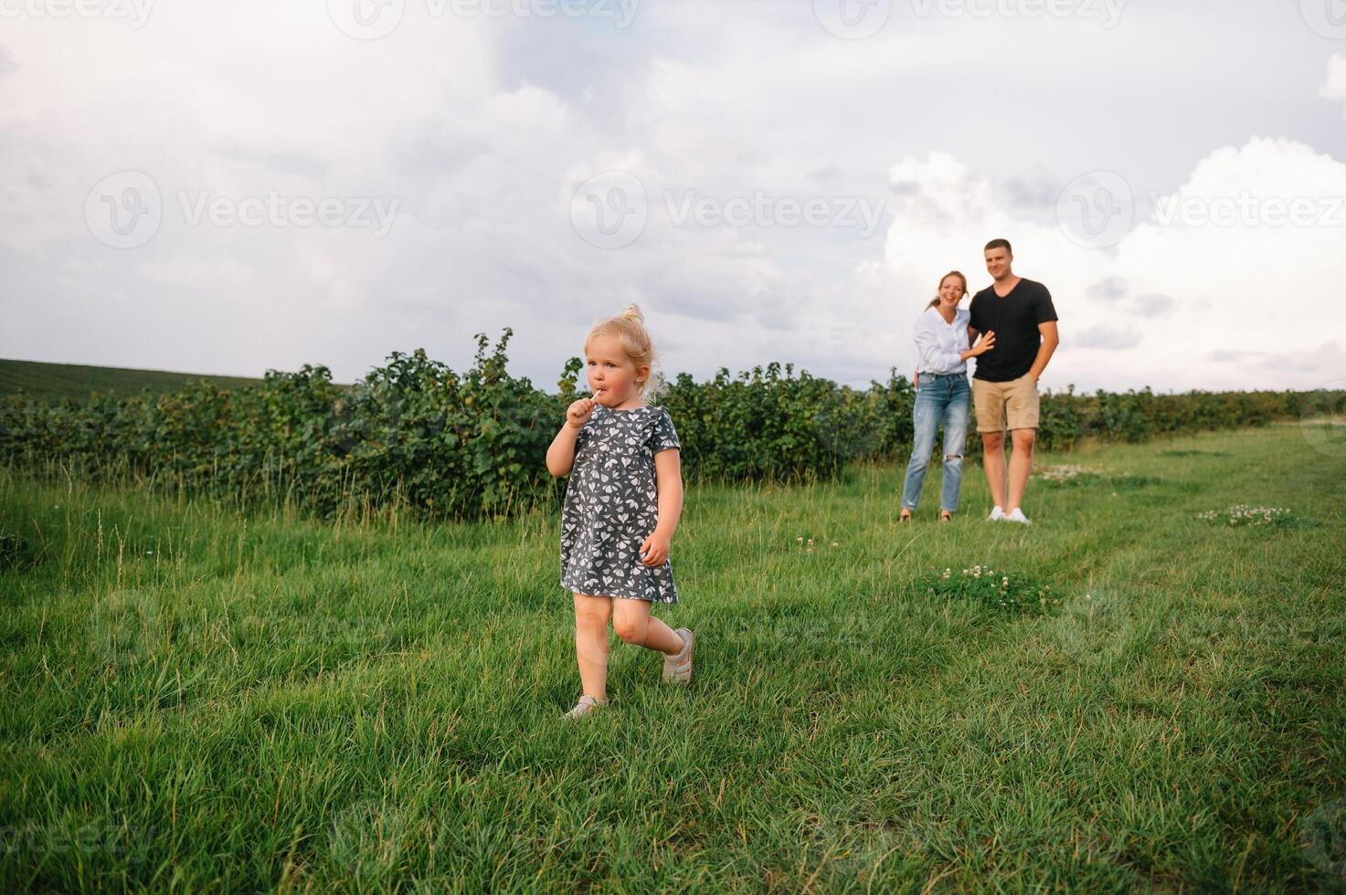 glücklich Familie Gehen im das Park. Mutter, Papa und Tochter gehen draußen, Eltern halten das Baby Mädchen Hände. Kindheit, Elternschaft, Familie Fesseln, Ehe Konzept. foto