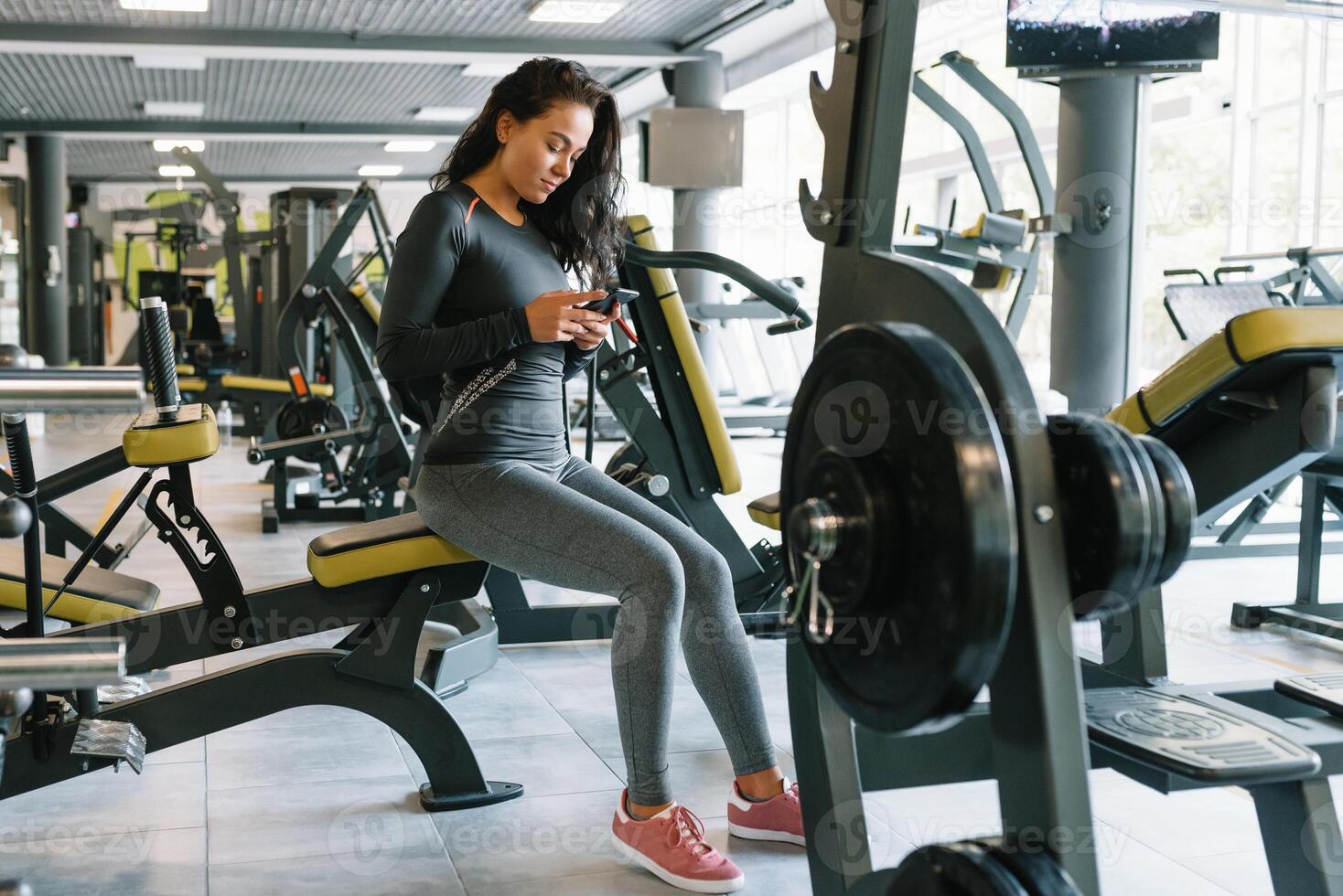 Herrlich jung Frau SMS und Sozial Vernetzung während im ein Fitnessstudio. foto