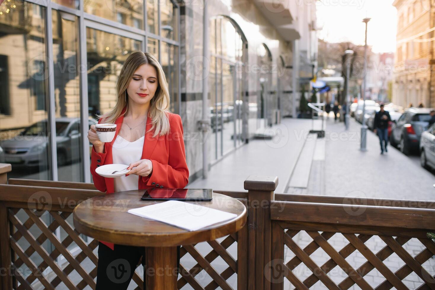 schön jung Geschäftsfrau mit ein Einweg Kaffee Tasse, Trinken Kaffee, und halten Tablette im ihr Hände gegen städtisch Stadt Hintergrund foto