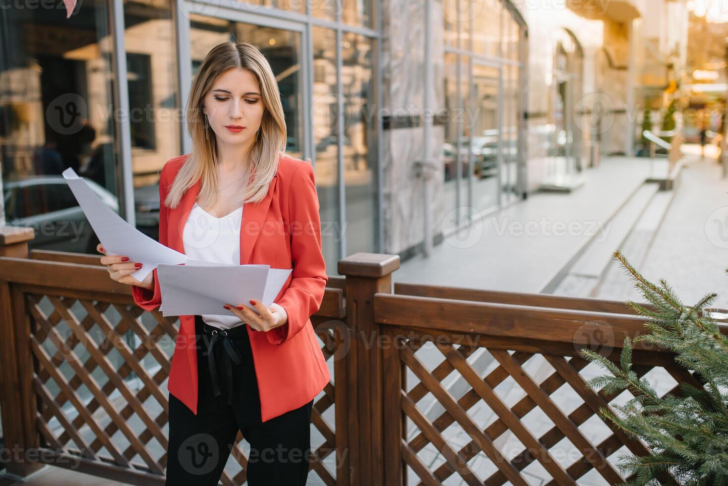 Porträt von Geschäft Frauen im Gefühl von konzentrieren Stress und sehen Stand und halt das Papier Datei Blatt im das draussen Fußgänger gehen Weg mit das Stadt Raum von Außen modern Fassade Gebäude foto