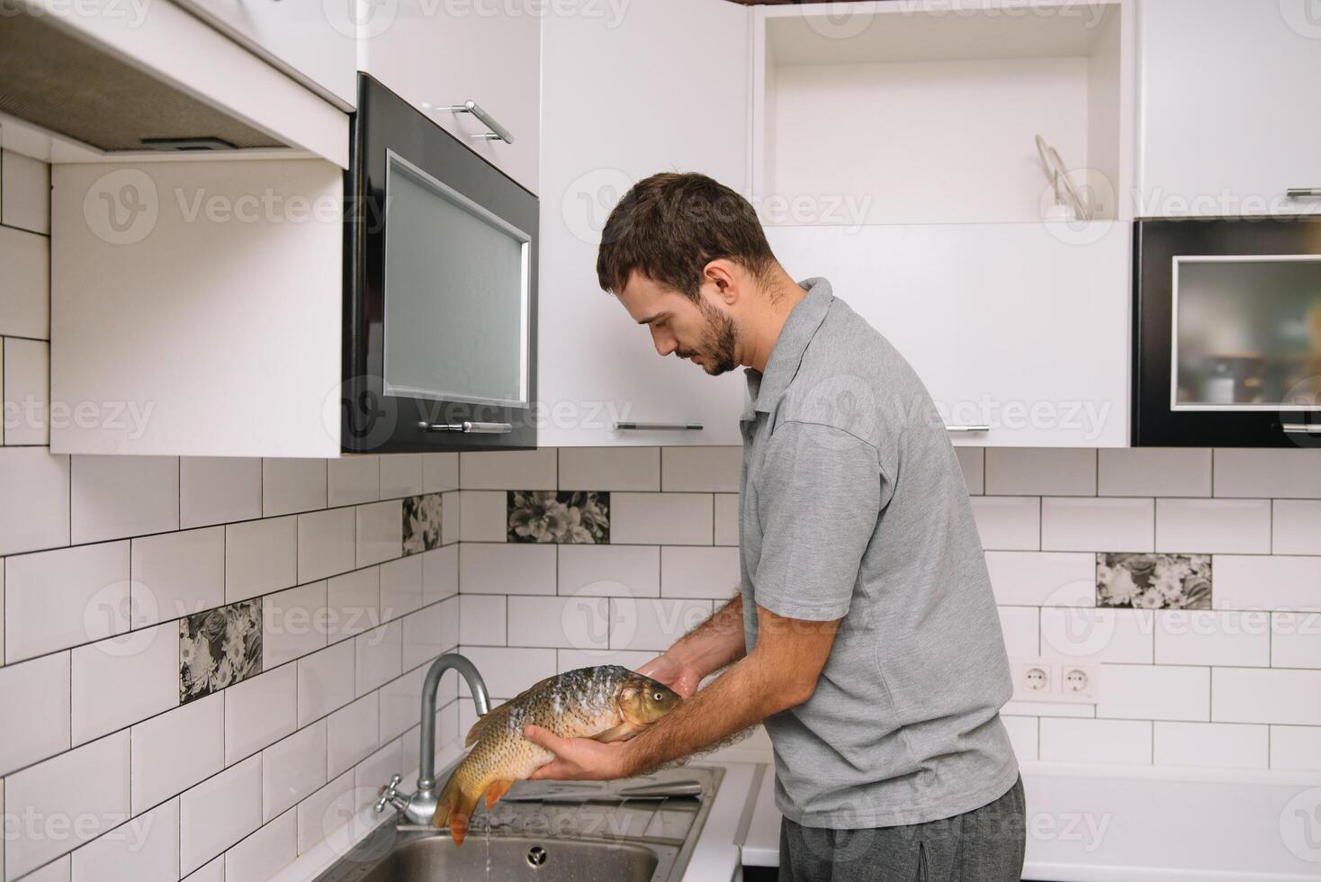 Mann Schneiden frisch Fisch im Küche im heim. Mann schlachten Fisch zum kochen. foto