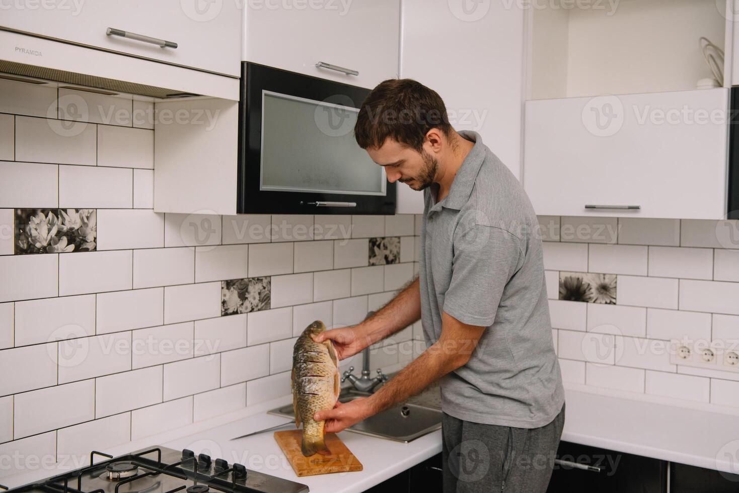 Mann Schneiden frisch Fisch im Küche im heim. Mann schlachten Fisch zum kochen. foto