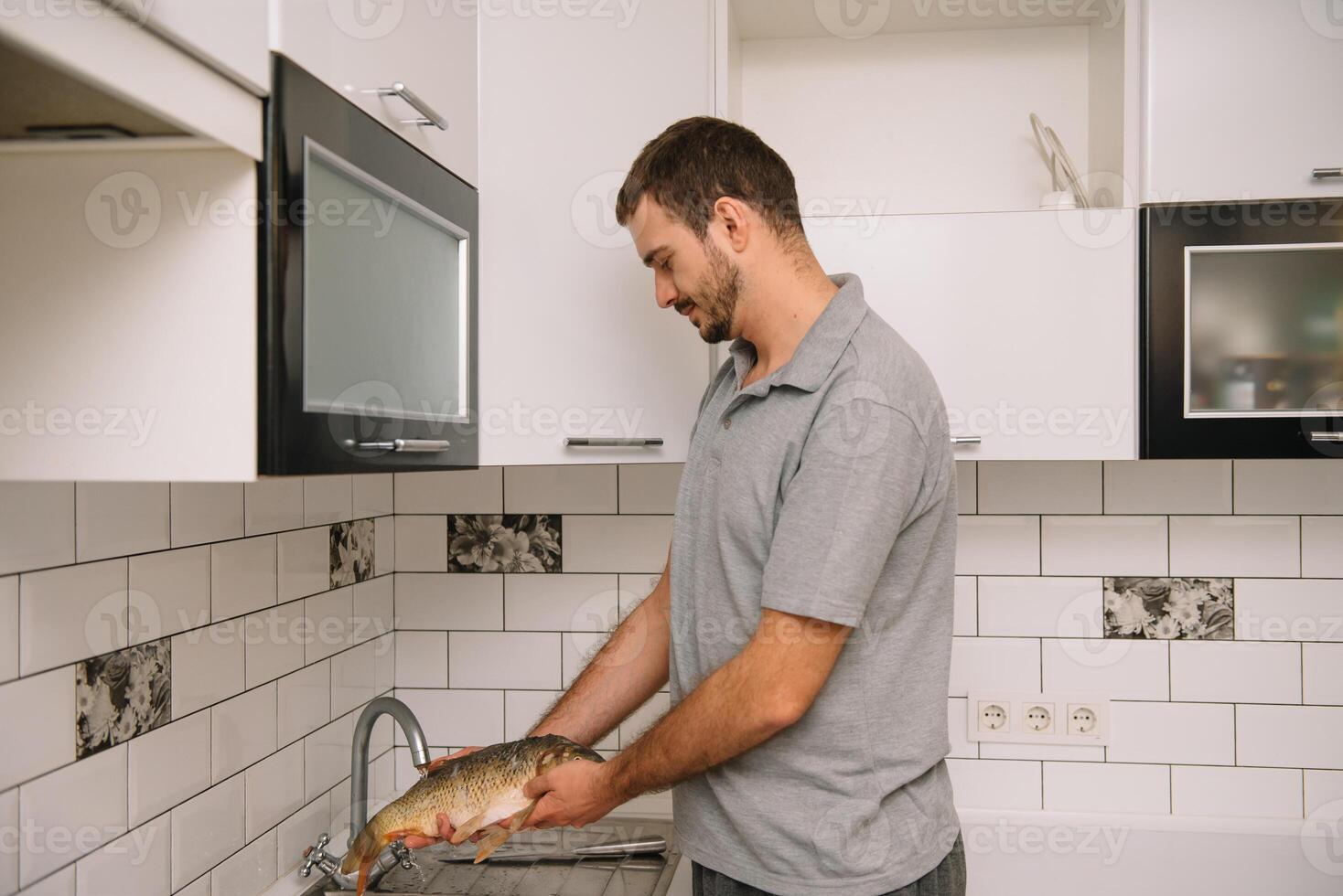 Mann Schneiden frisch Fisch im Küche im heim. Mann schlachten Fisch zum kochen. foto