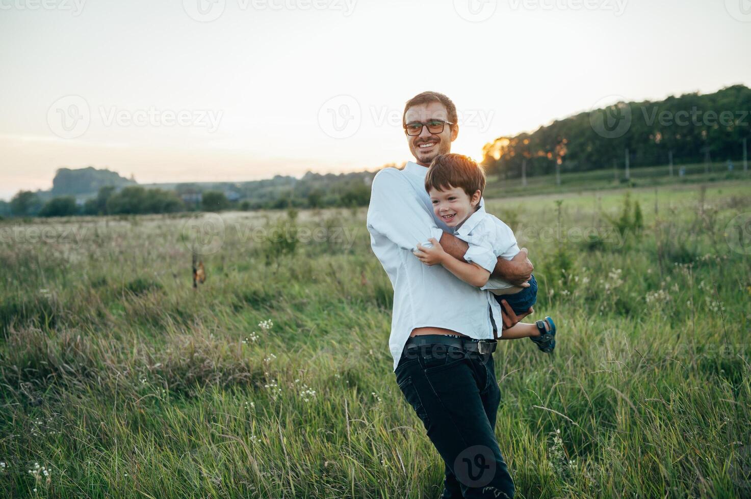 gut aussehend Papa mit seine wenig süß Sohn sind haben Spaß und spielen auf Grün grasig Rasen. glücklich Familie Konzept. Schönheit Natur Szene mit Familie draussen Lebensstil. Familie ruhen zusammen. Väter Tag. foto