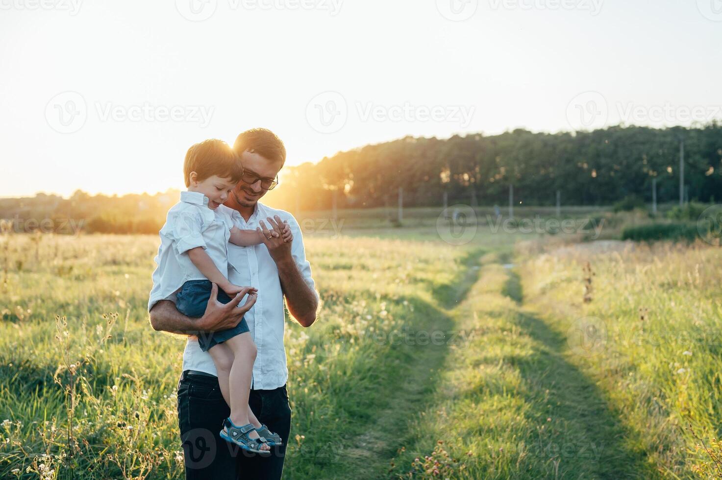 gut aussehend Papa mit seine wenig süß Sohn sind haben Spaß und spielen auf Grün grasig Rasen. glücklich Familie Konzept. Schönheit Natur Szene mit Familie draussen Lebensstil. Familie ruhen zusammen. Väter Tag. foto