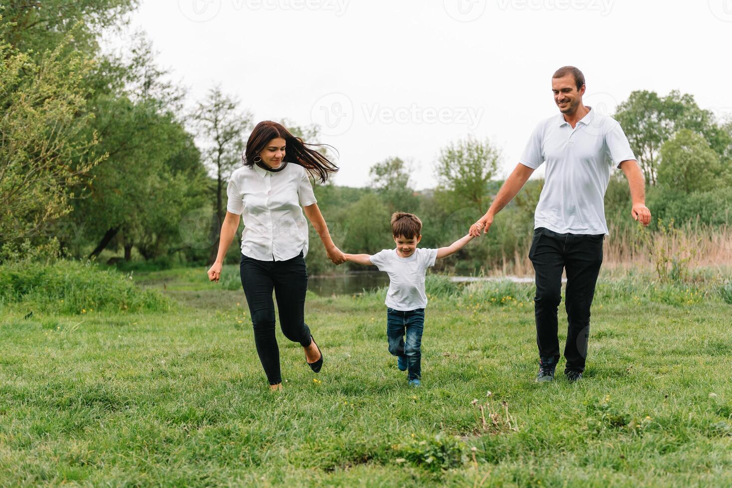 glücklich Familie Mutter Vater und Kind Sohn auf Natur auf Sonnenuntergang. Mutter, Papa und Kind Lachen und umarmen, genießen Natur außen. sonnig Tag, gut Stimmung. Konzept von ein glücklich Familie. foto