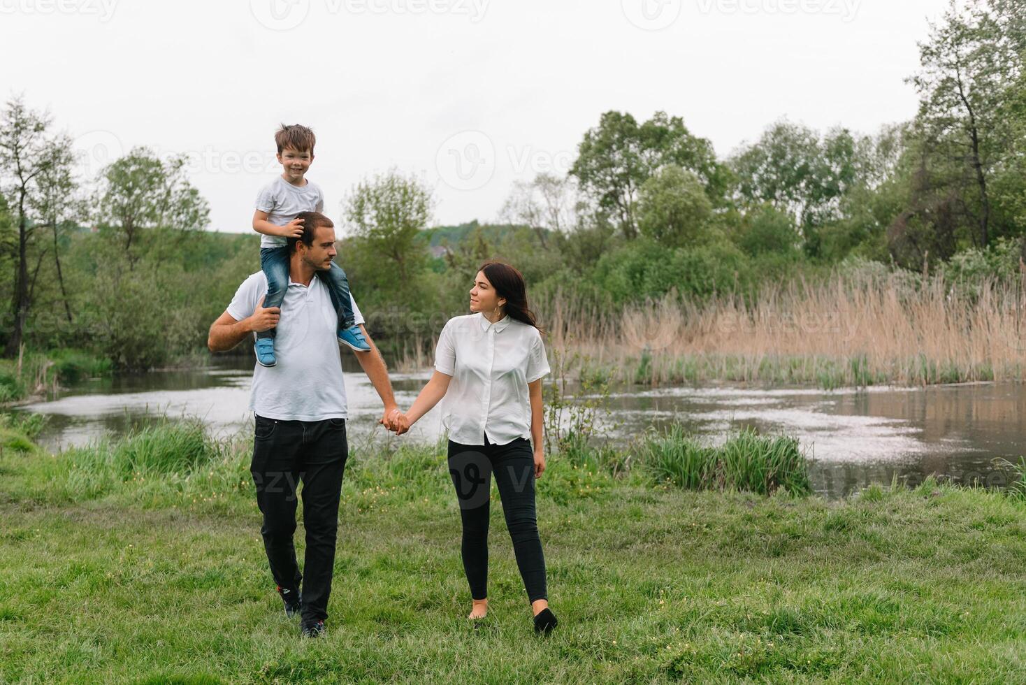 glücklich Familie Mutter Vater und Kind Sohn auf Natur auf Sonnenuntergang. Mutter, Papa und Kind Lachen und umarmen, genießen Natur außen. sonnig Tag, gut Stimmung. Konzept von ein glücklich Familie. foto