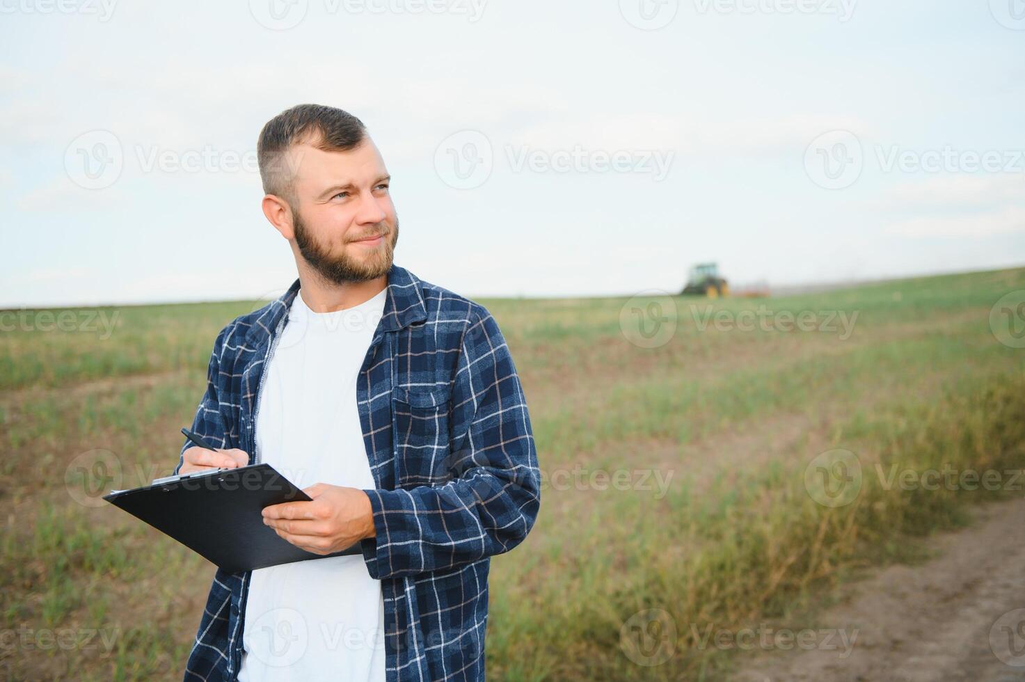 Farmer im ein Plaid Hemd kontrolliert seine Feld und Schreiben Anmerkungen. foto