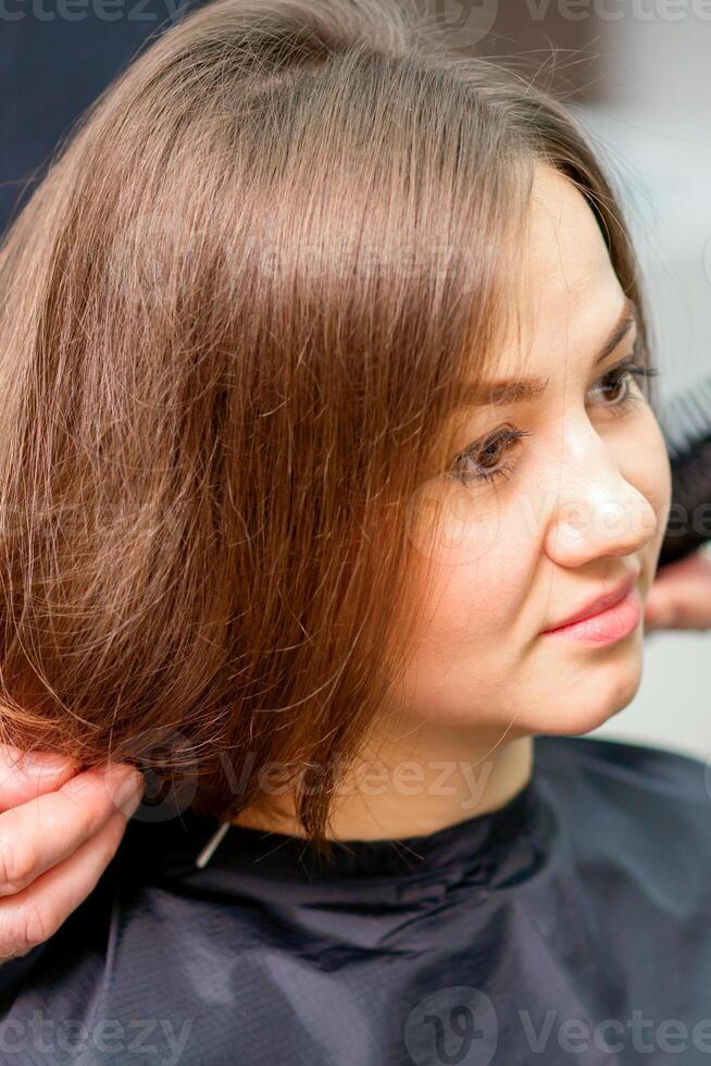 Styling weiblich Haar. männlich Friseur macht Frisur zum ein jung Frau im ein Schönheit Salon. foto