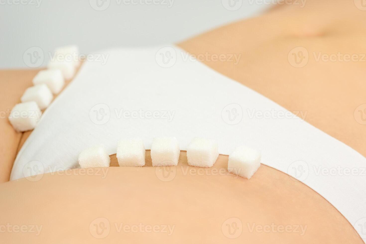 Zucker Würfel Lügen im ein Reihe auf weiblich Bikini Zone, das Konzept von intim Enthaarung, Probleme von intim Hygiene. foto