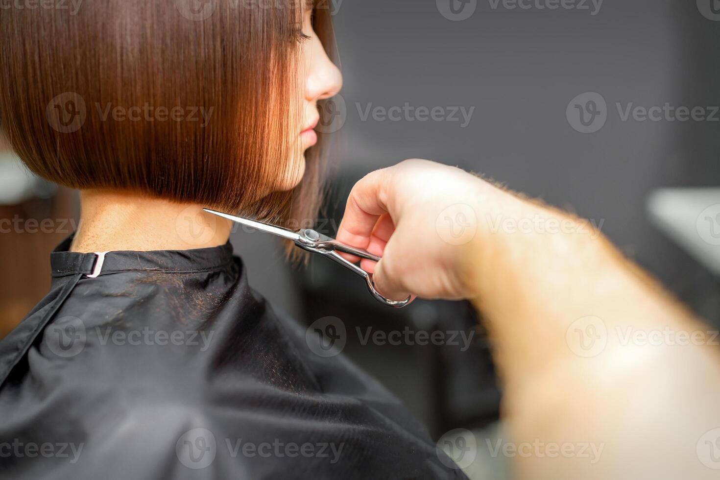 Frau haben ein Neu Haarschnitt. männlich Friseur Schneiden braun Haar mit Schere im ein Haar Salon. foto