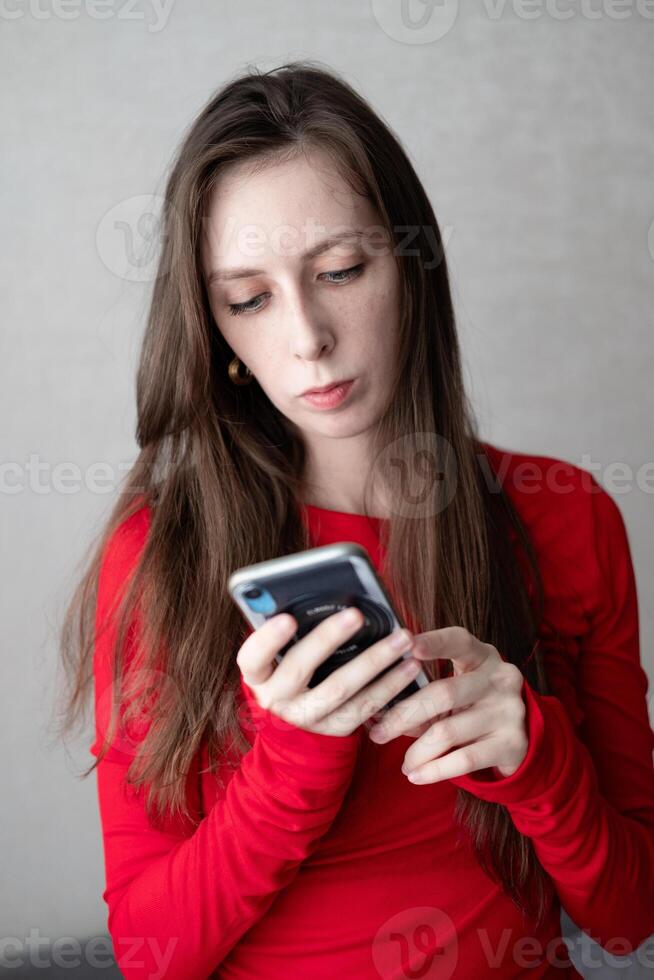 schön jung Frau mit Blau Augen und lange Haar im ein schön Jacke Uhren das Nachrichten auf das Telefon foto