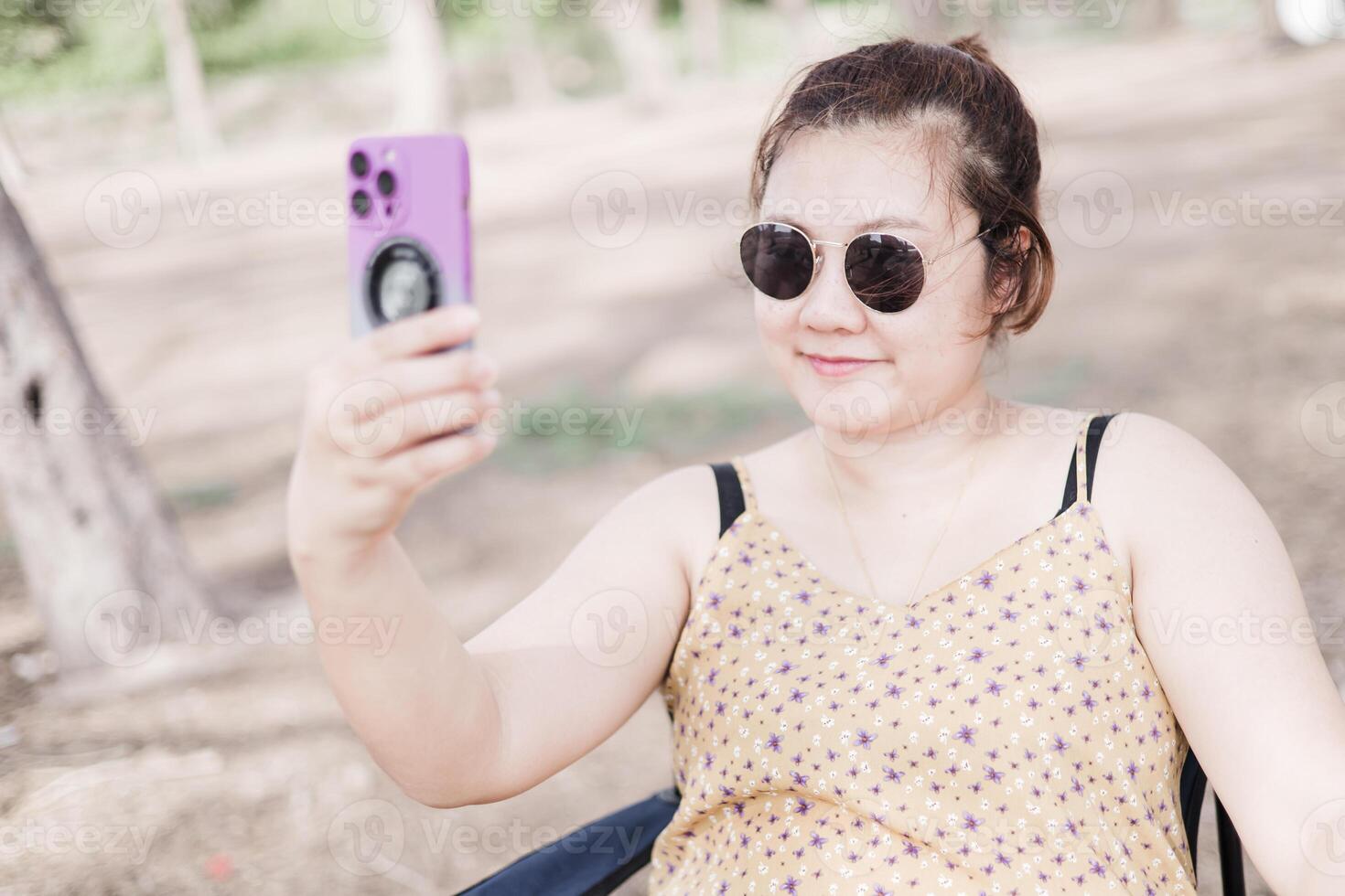 Frau tragen dunkel Brille lächelnd und nehmen Selfie im das Park. foto