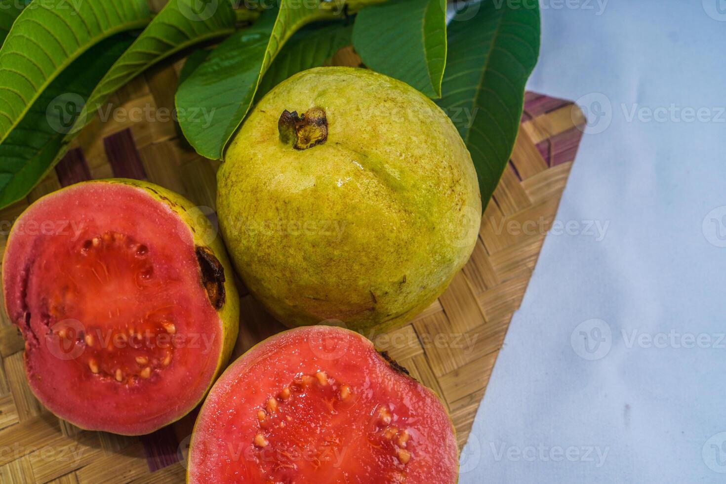 Guave isoliert. Sammlung von rot fleischig Guave Obst mit gelblich Grün Haut und Blätter isoliert auf ein Weiß Hintergrund mit Bambus Matten. foto