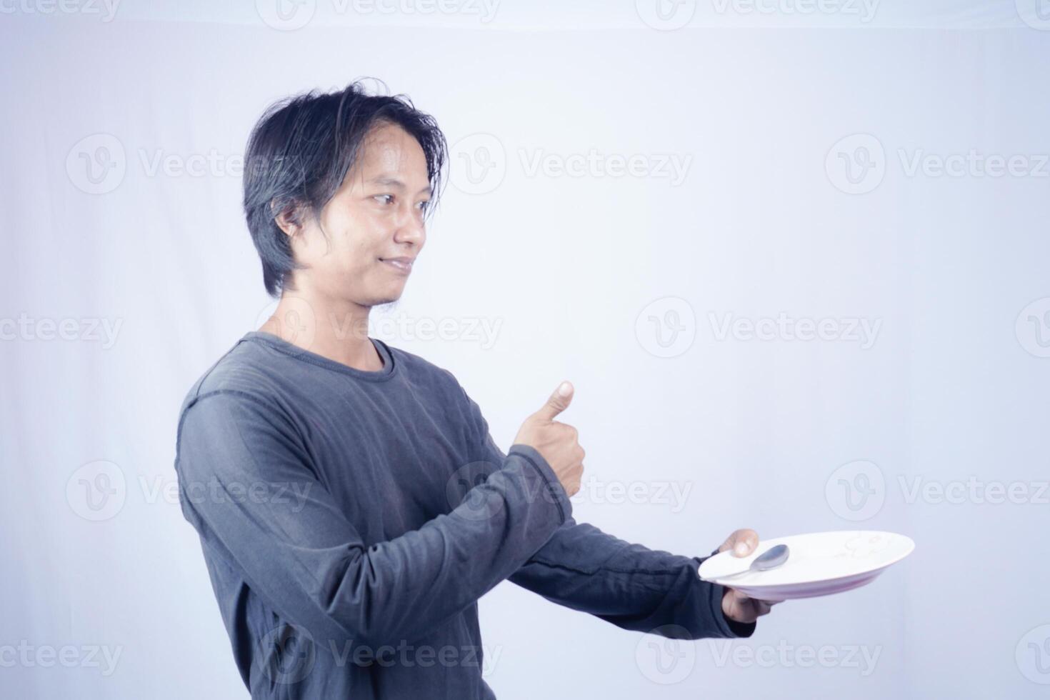 schließen oben Aussicht von gut aussehend asiatisch Mann halten Teller mit glücklich Ausdruck, zeigen Das das Essen ist köstlich auf isoliert Weiß Hintergrund zum Werbung. foto