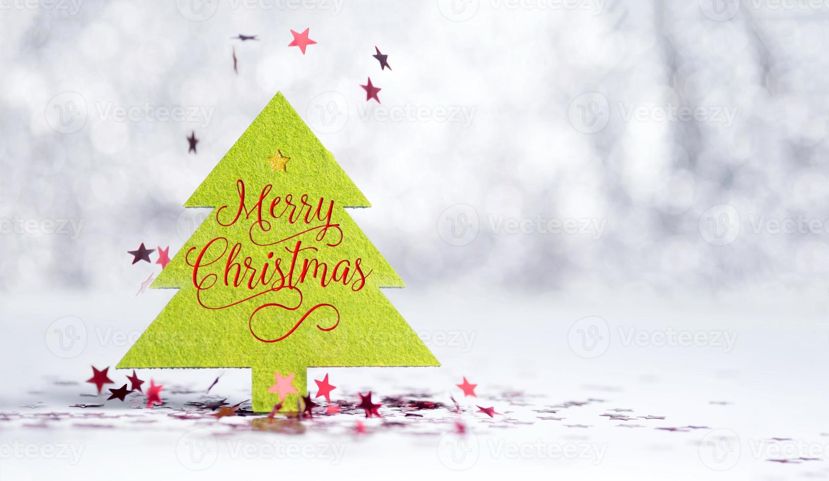 Nahaufnahme Frohe Weihnachten Wort auf grünem Weihnachtsbaum mit funkelnden roten Stern foto