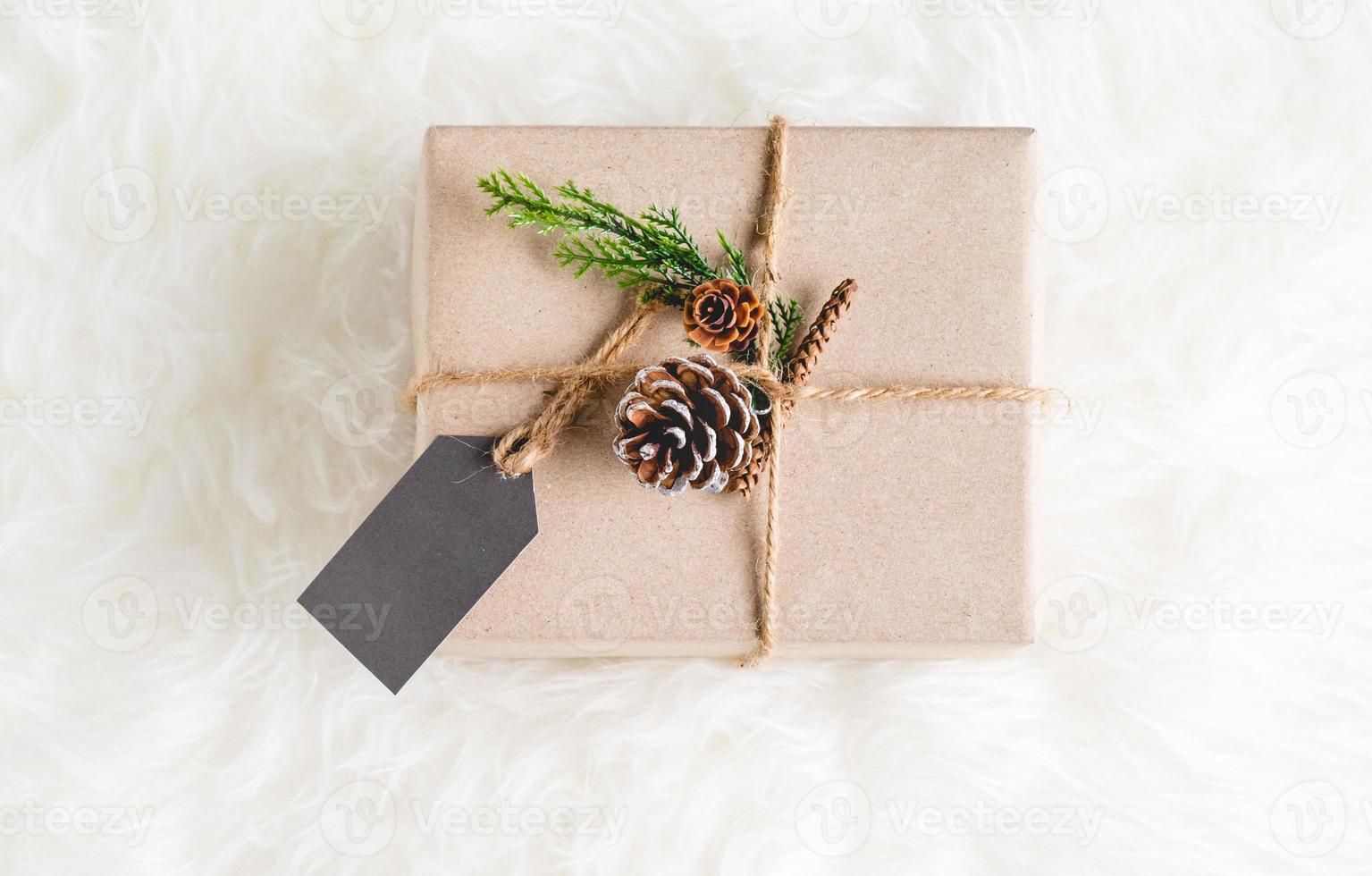 braunes Papierhandwerk verzogen auf Geschenkbox mit Tannenzapfen und grünem Blatt dekorieren foto