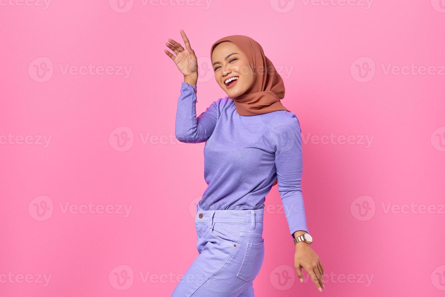 Porträt der schönen jungen asiatischen Frau, die glücklich und fröhlich auf rosa Hintergrund tanzt foto