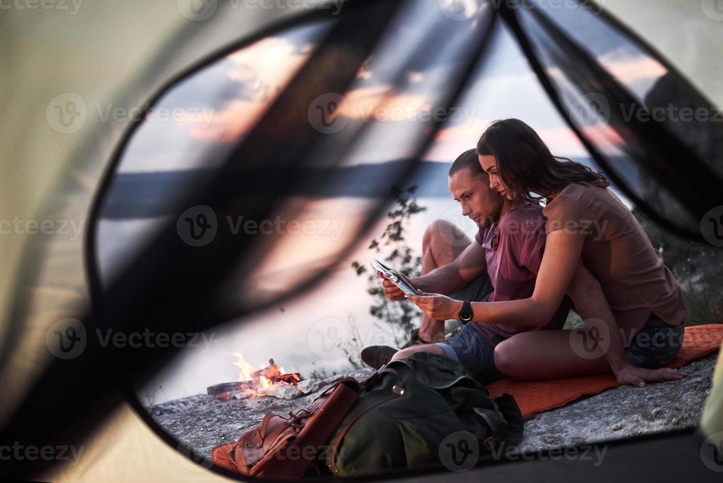 Blick vom Zelt eines Paares mit einer Karte, die während der Wanderung einen Blick auf den See hat. Avel Lifestyle Konzept Abenteuerurlaub im Freien foto