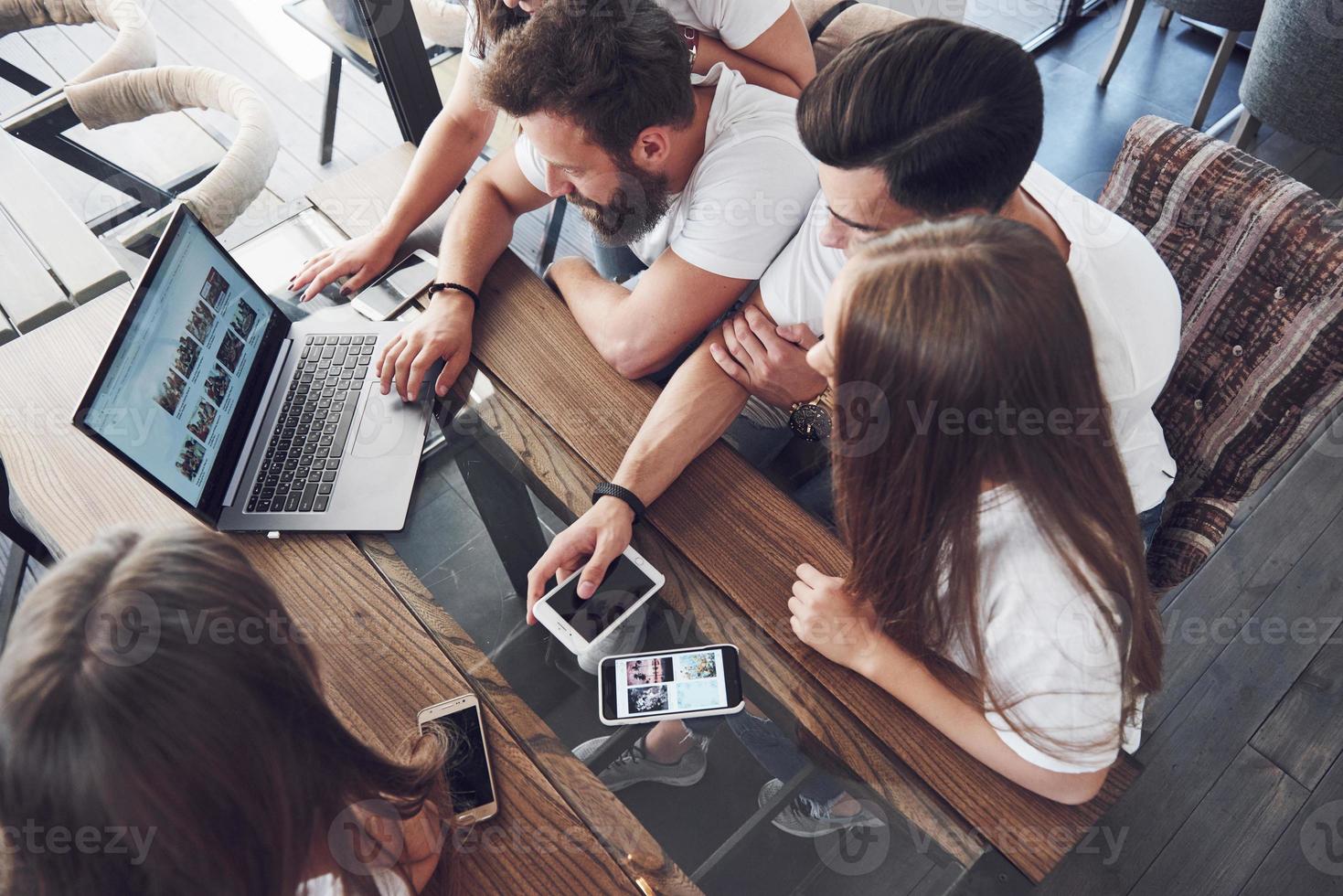 eine Gruppe junger Leute mit Gadgets und einem Laptop verabredet ein Brainstorming und kommuniziert miteinander. das Konzept der Entwicklung eines jungen Unternehmens foto