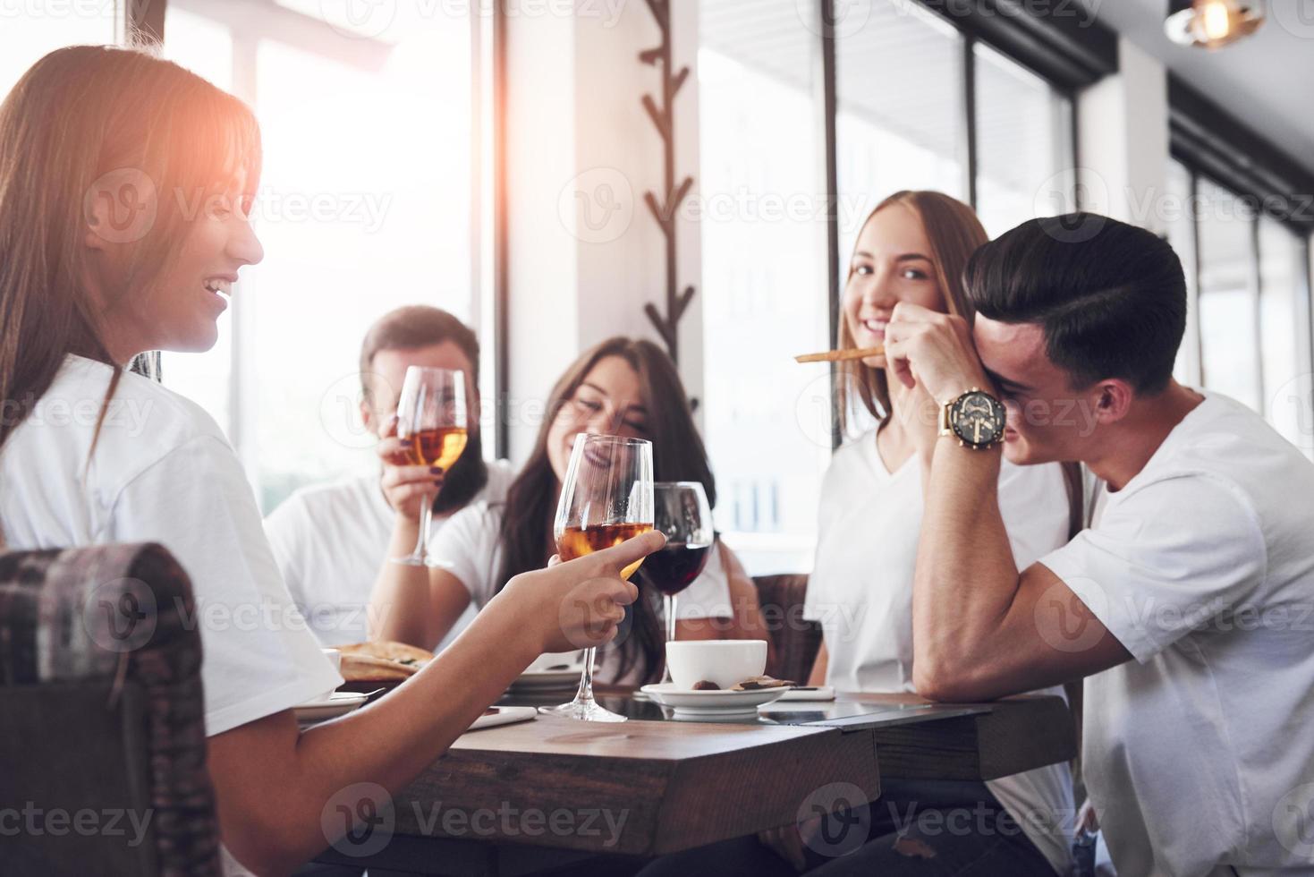 Freunde trafen sich am Tisch bei leckerem Essen mit Gläsern Rotwein, um einen besonderen Anlass zu feiern foto