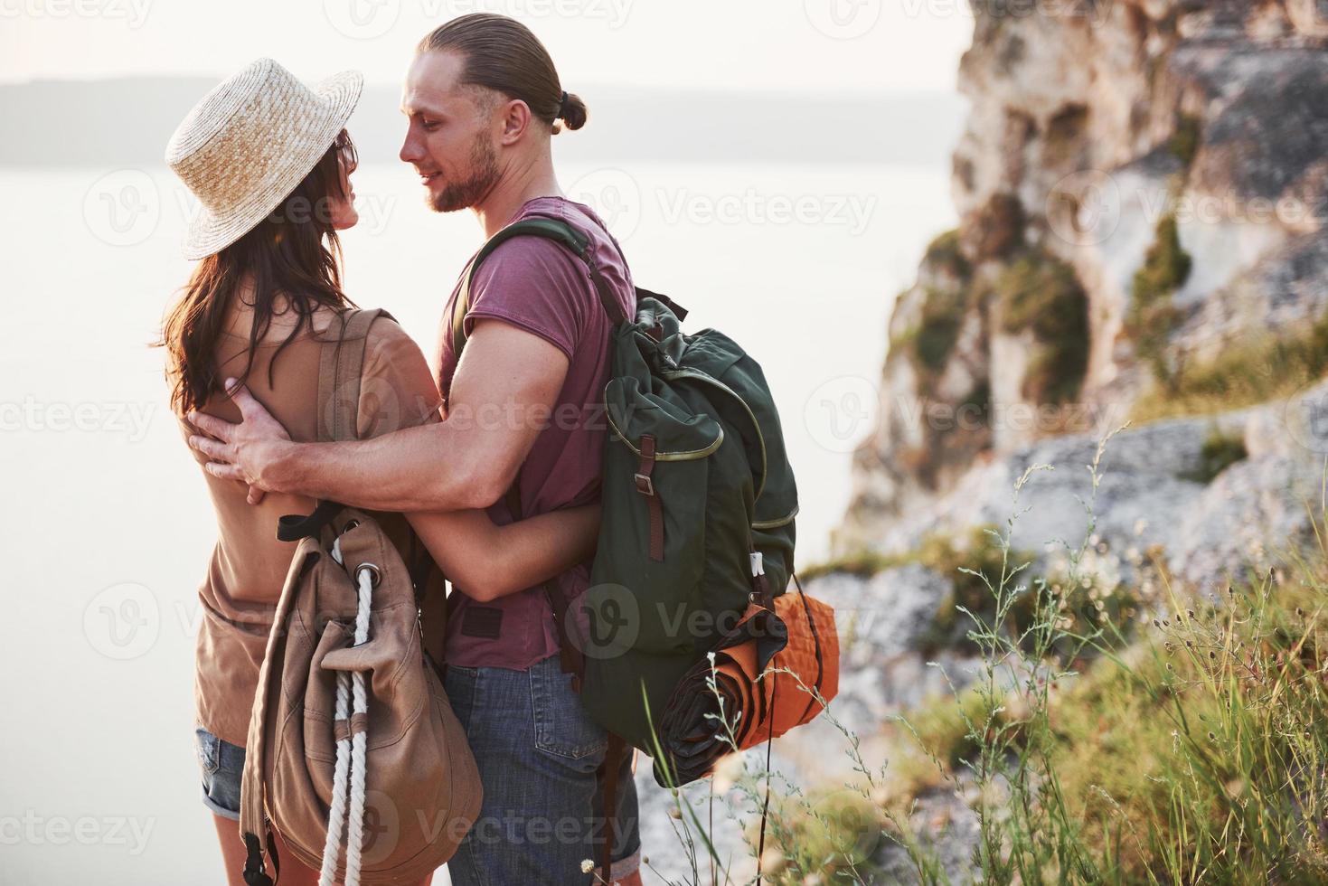 Zwei touristische Männer und Frauen mit Rucksäcken stehen auf dem Gipfel des Berges und genießen den Sonnenaufgang. Reise-Lifestyle-Abenteuer-Urlaub-Konzept foto