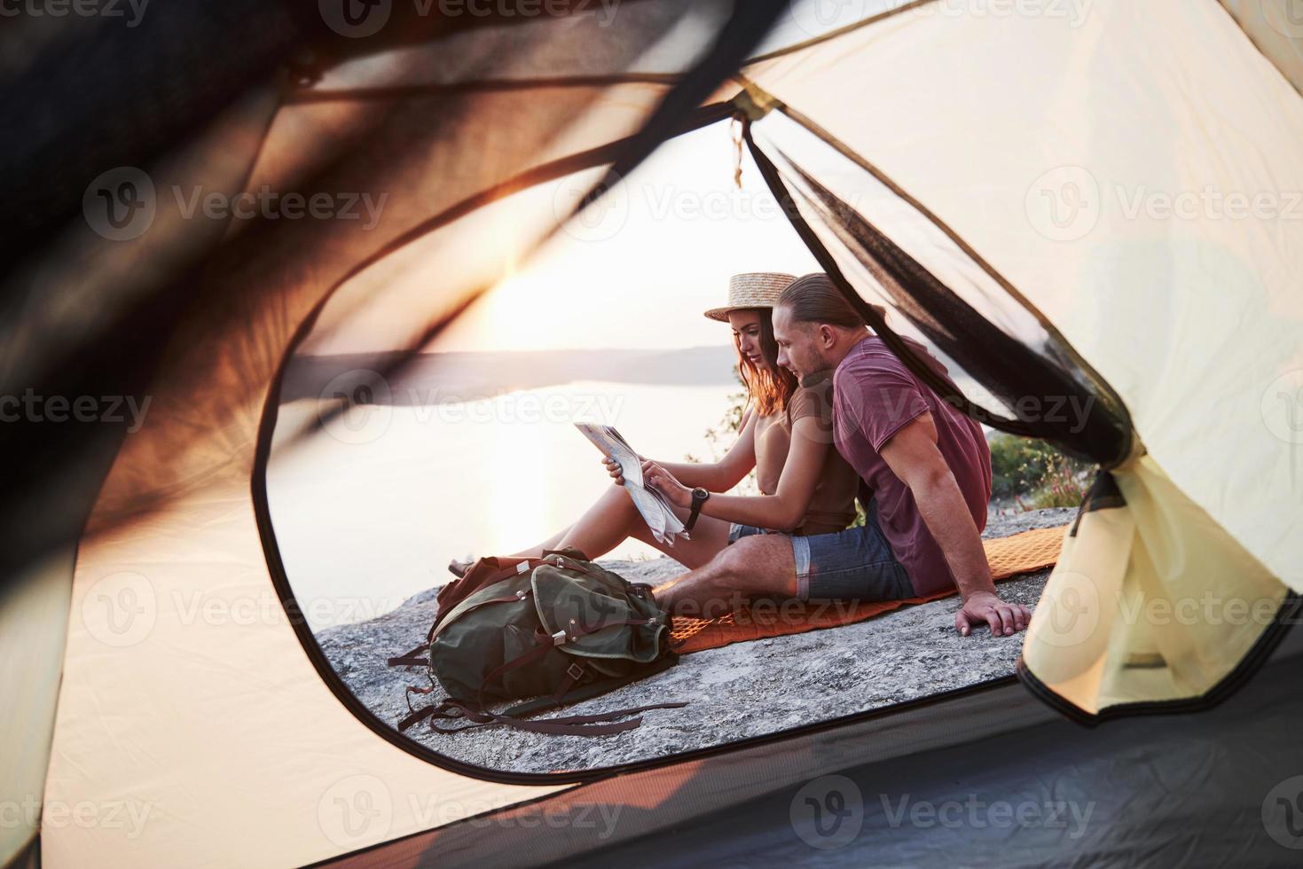 Blick vom Zelt eines Paares mit einer Karte, die während der Wanderung einen Blick auf den See hat. Avel Lifestyle Konzept Abenteuerurlaub im Freien foto