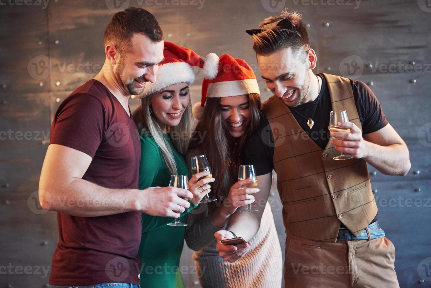 fröhliche alte freunde kommunizieren miteinander und telefonieren, mit gläsern champagner in der neujahrsparty. Konzept der Unterhaltung und des Lebensstils. WLAN-verbundene Menschen foto