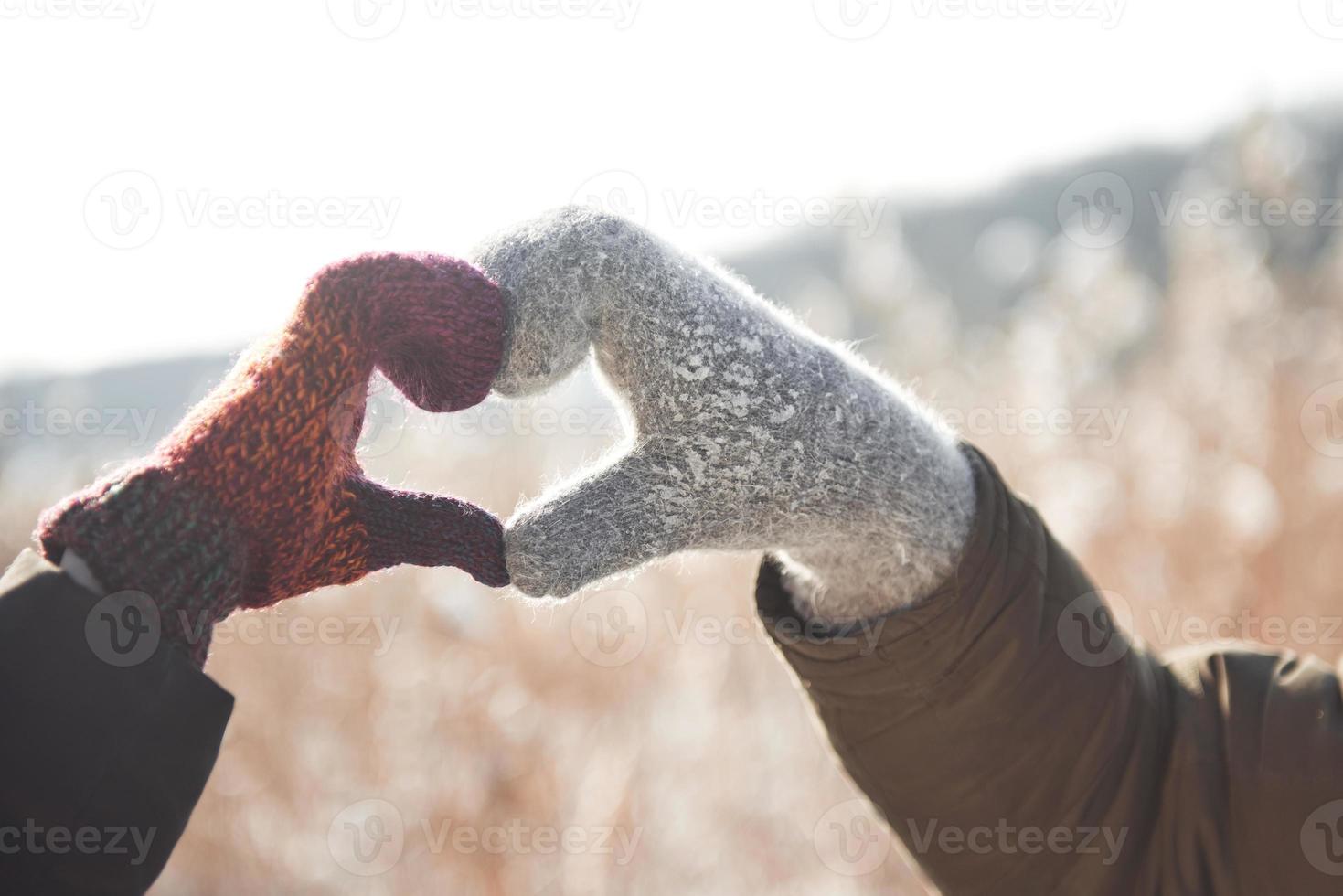 Frauen- und Männerhände im Handschuh gefaltet in Herzform. Winterkonzept. Schneefall. foto