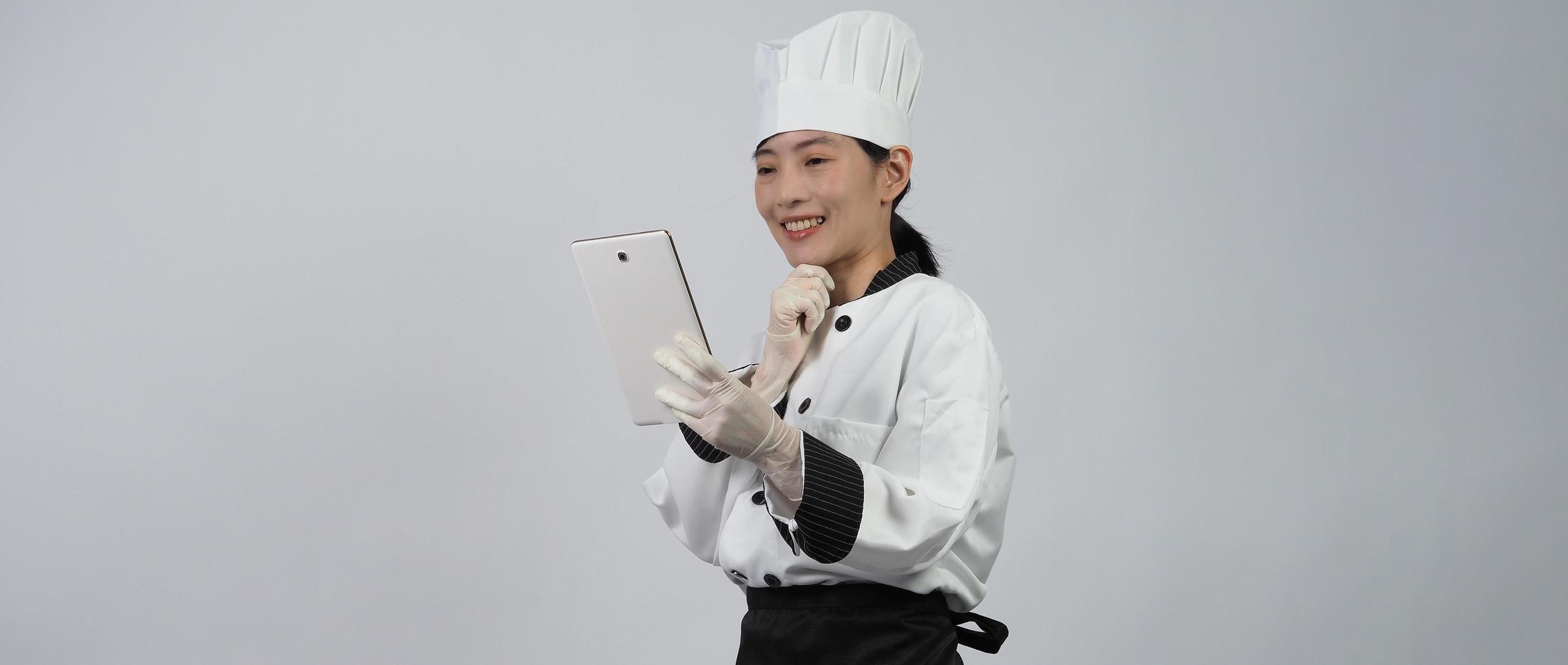 Asiatische Köchin, die Smartphone oder digitales Tablet hält und Bestellung von online erhalten hat foto