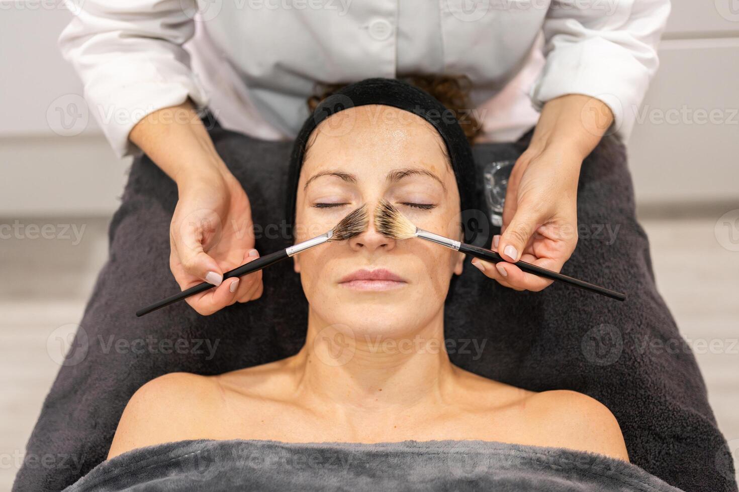 Kosmetikerin bewirbt sich Kosmetika auf Klient im Schönheit Salon foto