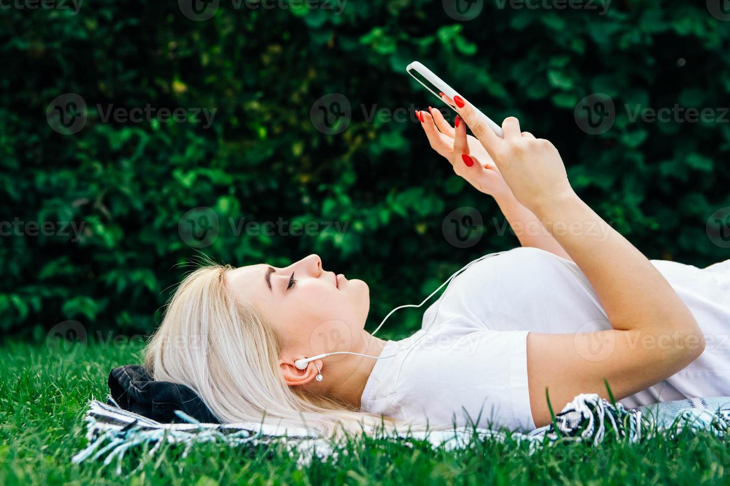 Frau mit Kopfhörern und Smartphone auf grünem Hintergrund foto