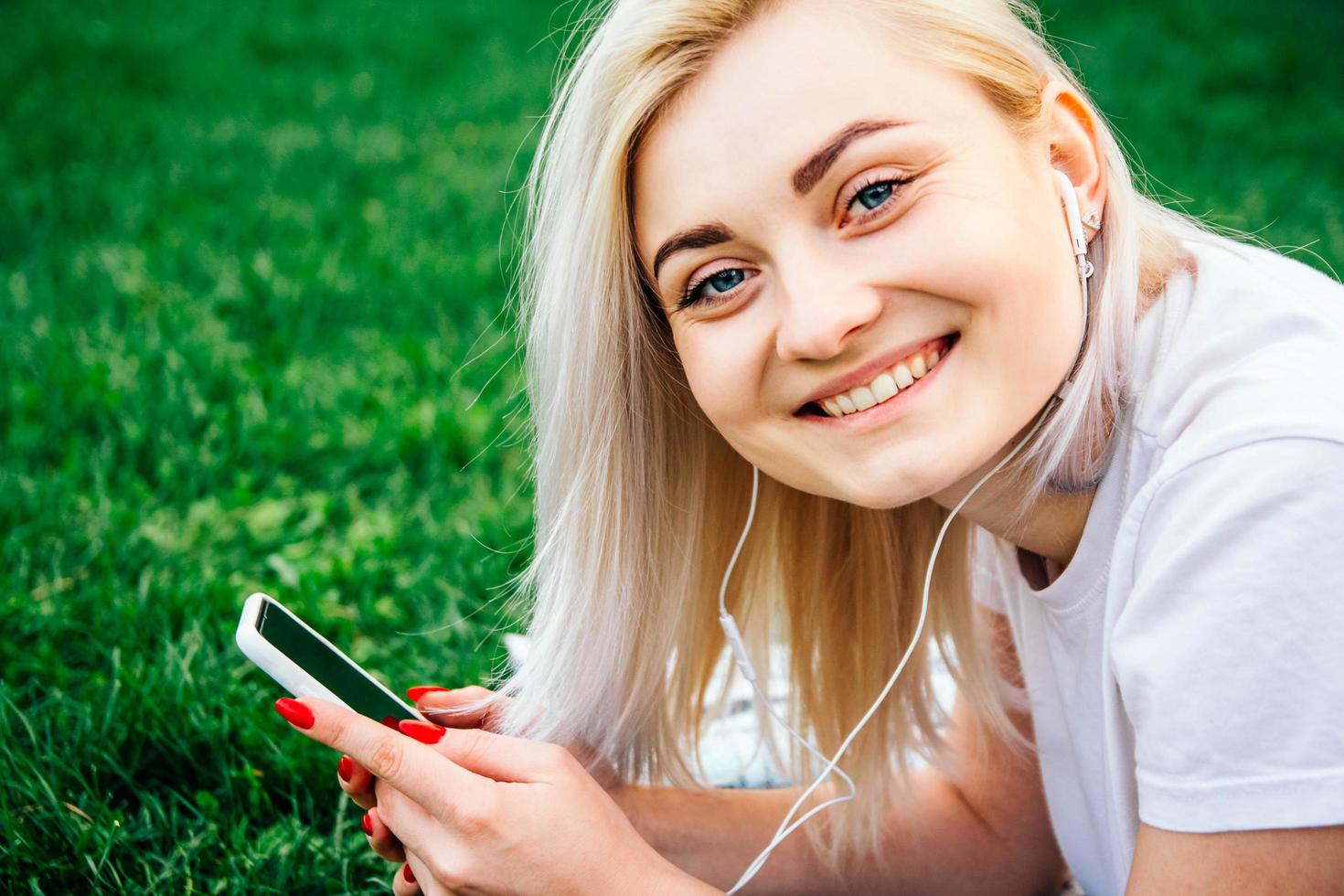 Frau mit Kopfhörern und Smartphone in den Händen hört Musik foto